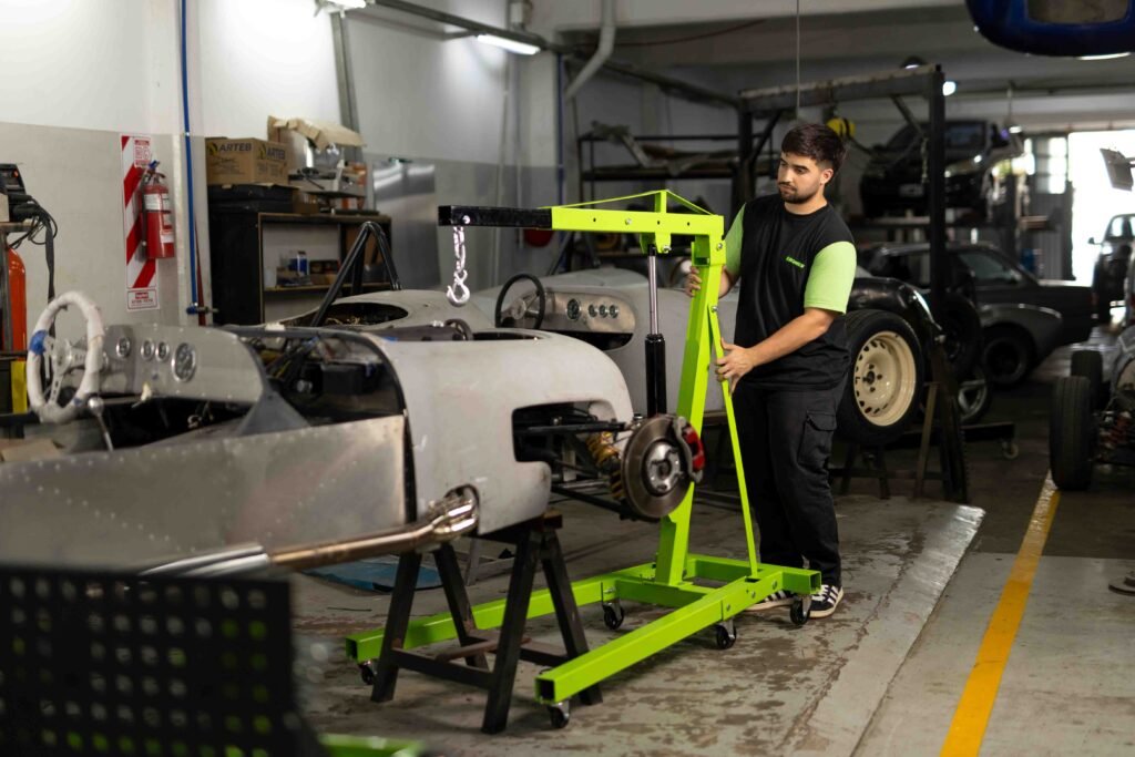 JMC36481-72 Vista general del taller con equipamiento Kroner, vehículo en reparación y mecánico