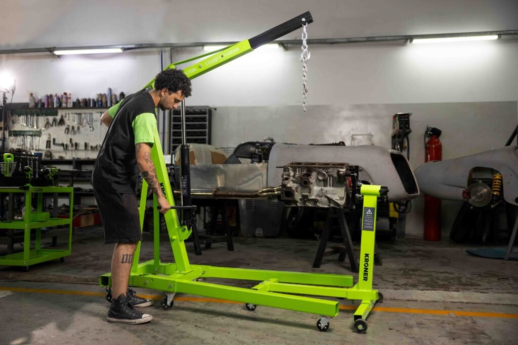 JMC36544-Editar-84 Mecánico operando la grúa de taller Kroner con el brazo extendido junto a un auto